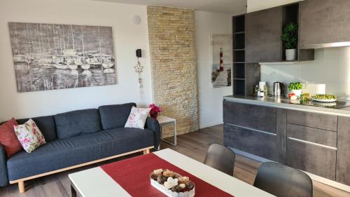 a living room with a blue couch and a kitchen at Vila Primorka Apartmani Oleander in Šilo