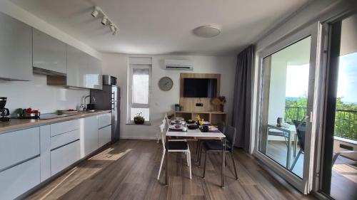 a kitchen with white cabinets and a table with chairs at Vila Primorka Apartmani Oleander in Šilo