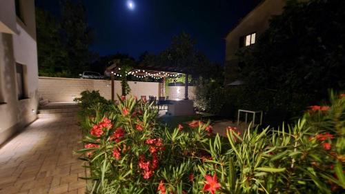 a garden with flowers and a fence at night at Vila Primorka Apartmani Oleander in Šilo