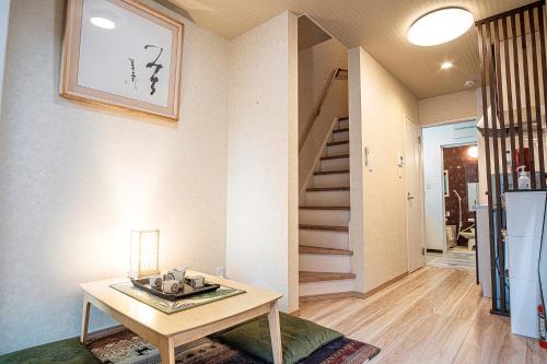 a living room with a table and a staircase at Bungetsu Shokaku Kaikan in Kyoto