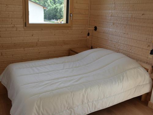 a white bed in a room with a window at Chalet neuf 4 pièces - À deux pas du centre, téléphérique et loisirs - FR-1-464-188 in Pralognan-la-Vanoise