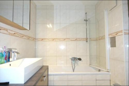 biała łazienka z wanną i umywalką w obiekcie Top Apartment in Langenhagen w Hanowerze