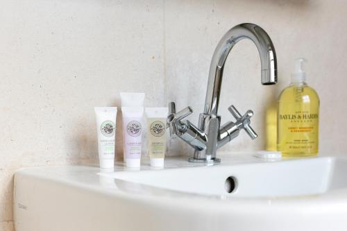 a sink with three bottles of moisturizers on it at PenthouseStays Notting Hill - Chic 2 Bedroom Apartment w/ King Beds - near Portobello Road & Kensington High Street in London