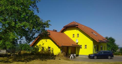 a yellow house with a car parked in front of it at Urlaub mit Hund auf dem Bauernhof Hofswald in Euscheid
