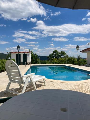 a white chair sitting next to a swimming pool at Monte das Cerejas in Montes da Senhora