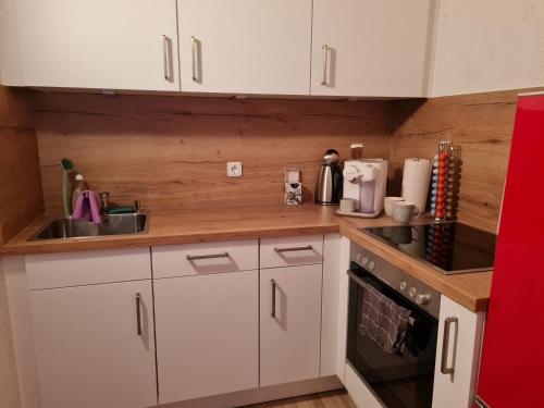 a kitchen with white cabinets and a sink and a stove at Ferienwohnung am See mit Bergblick & Sonnenbalkon in Blaichach