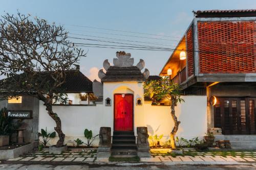 a small white house with a red door at Rumah Paros & Gallery in Sukawati