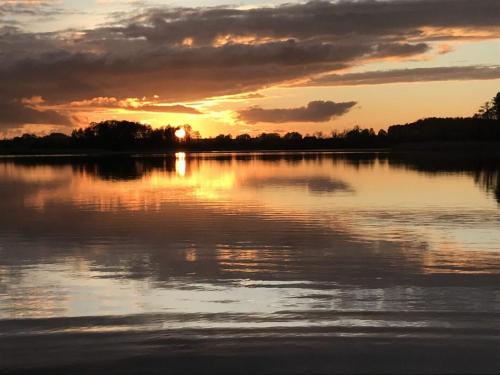 a sunset over a large body of water at Cisy Resort-bon turystyczny,,ogrodzony teren na wyłączność,150 m od jeziora in Makosieje