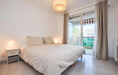 a white bedroom with a large bed and a window at Amazing Apartment In Cannes With Wifi in Cannes