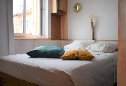 two pillows sitting on top of a bed with a window at Studio sympa avec petit déjeuner entre canal et Loire in Roanne