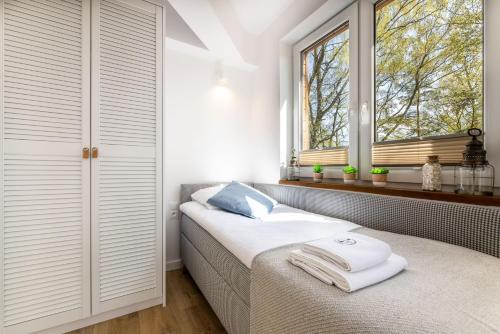 a bedroom with a bed and two windows at Apartament 20B Blue Marine Poddąbie in Poddąbie