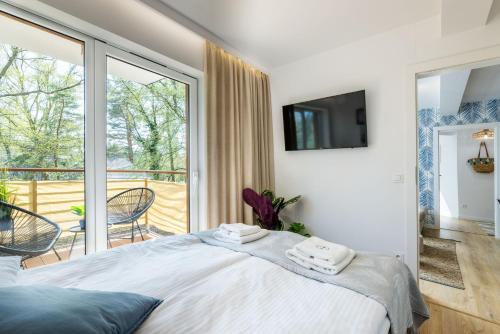 a bedroom with a large bed and a balcony at Apartament 20B Blue Marine Poddąbie in Poddąbie