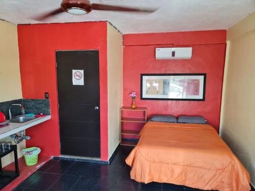 Cette chambre rouge comprend un lit et un mur rouge. dans l'établissement Independent Apartment Wifi A C, Stove, Refrigerator, Tv, à Mérida