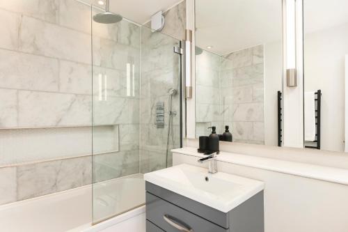 uma casa de banho branca com um lavatório e um chuveiro em PenthouseStays Chelsea - Luxury 2 Bedroom Apartment w/King Bed - near King's Road em Londres