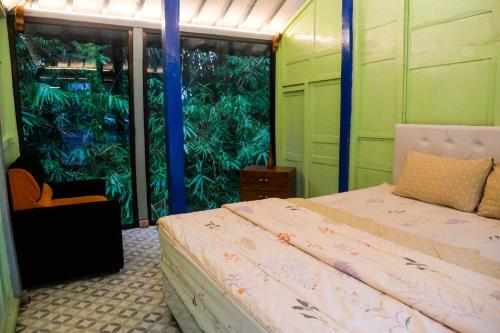 - une chambre avec un lit et une grande fenêtre dans l'établissement Villa Kamar Tamu Selomartani 2, à Sleman