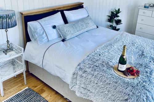 Wavecrest Holiday Cottage في غاريفوي: غرفة نوم مع سرير مع زجاجة من الشمبانيا