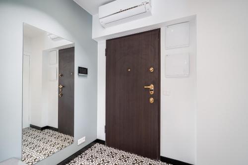 a hallway with two brown doors and white walls at Kasztelanska Old Town Deluxe Apartment WAWELOFTS in Kraków