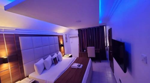 a bedroom with a large white bed and a television at Presken Hotel and Resorts MOJIDI in Ikeja