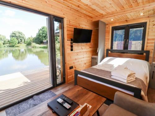 a bedroom with a bed and a large window at Maple Lodge at Bridge Lake Farm & Fishery in Banbury