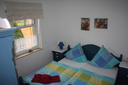 a bedroom with a bed with colorful pillows and a window at Ferienwohnung 1066 App 3 in Tossens in Tossens