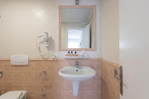 La salle de bains est pourvue d'un lavabo, d'un miroir et de toilettes. dans l'établissement HomeForGuest Apartamento Alisios 1 con piscina en Corralejo, à Corralejo