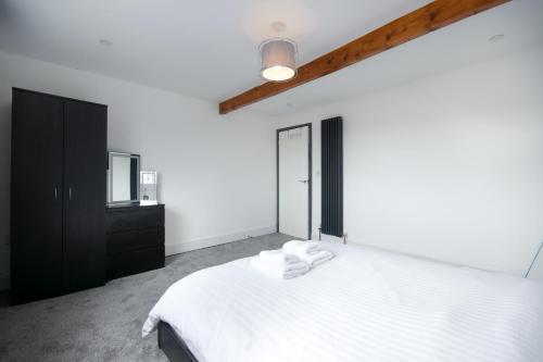 um quarto com uma cama branca e um armário preto em Beautiful Apartment by Town & Beach em Swansea