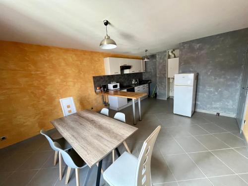 La cuisine est équipée d'une table, de chaises et d'un réfrigérateur. dans l'établissement Appartement 2 chambres - lits king size - wifi - baignoire, au Puy-en-Velay