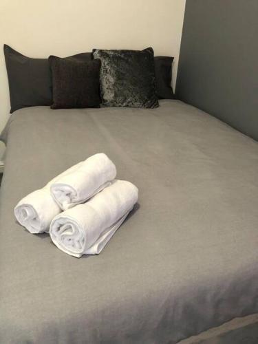 dois rolos de toalhas sentados numa cama em 1 BR Flat in Central Stoke Near Train Station em Stoke-on-Trent