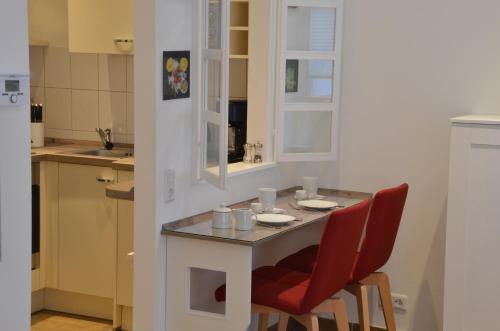 uma pequena cozinha com uma mesa e duas cadeiras vermelhas em Altbau trifft Moderne, neuwertige Komfortwohnung für bis 2 Personen em Wuppertal