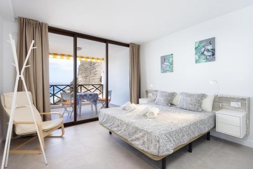 ein Schlafzimmer mit einem Bett und einem Stuhl sowie einem Balkon in der Unterkunft 120 PLAYA DE LA ARENA Holiday Home by Sunkeyrents in Puerto de Santiago