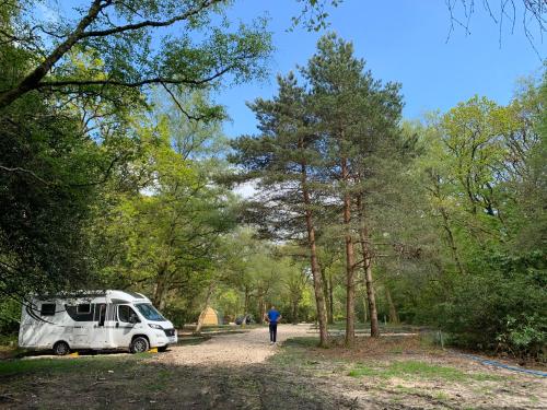 a man walking down a dirt road next to a camper at Nuthatch Cabin at Cloudshill Glade in Wareham