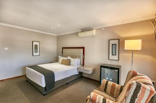 Habitación de hotel con 1 cama y 2 sillas en Regent Kgale Lodge en Gaborone