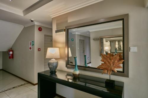 a room with a mirror and a table with a lamp at Regent Kgale Lodge in Gaborone