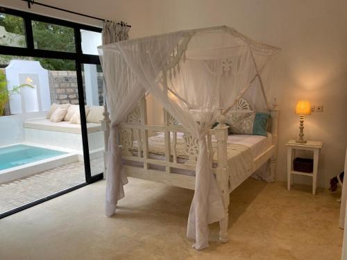 1 dormitorio con cama con dosel y piscina en Nyumba Nyekundu, en Watamu