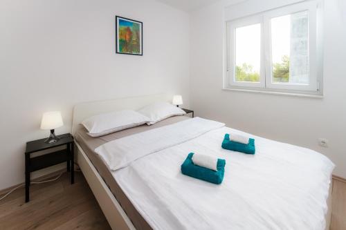 białe łóżko z dwoma niebieskimi poduszkami w obiekcie APARTMENT ANNA w mieście Rijeka