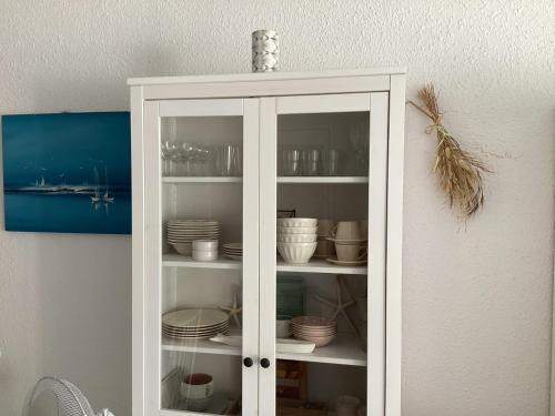 une armoire blanche remplie de plaques et de bols dans l'établissement Le serpent de mer, au Grau-du-Roi