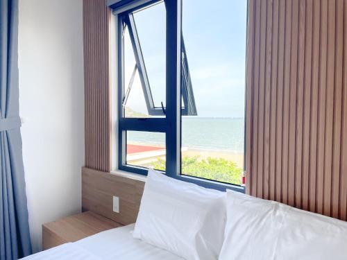 a bedroom with a window with a view of the ocean at HAKU Boutique Hotel in Quy Nhon