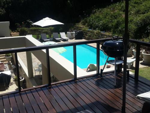 a deck with a pool with chairs and an umbrella at The Greens Guesthouse Bellville Golf Course in Bellville