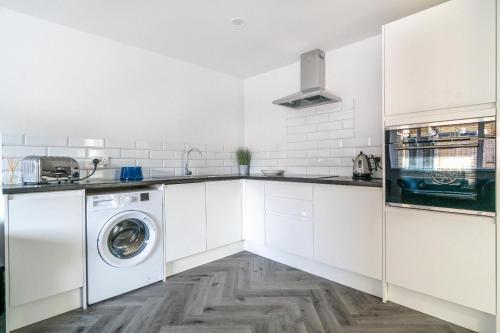 a white kitchen with a washing machine in it at Gresham in Kent
