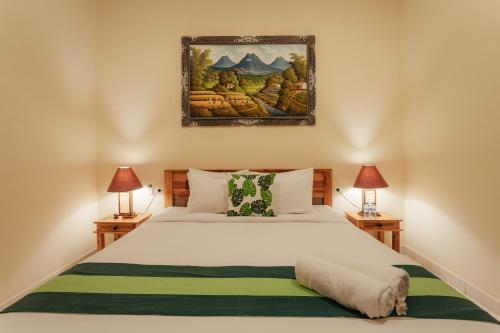 a bedroom with a large bed with two lamps at BUBU CANGGU Guesthouse in Canggu