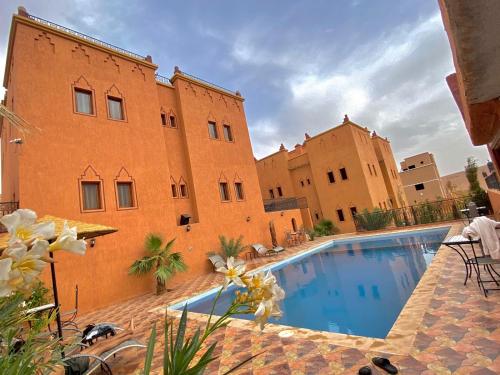 a building with a swimming pool in front of a building at Riad Ouinz in Aït Ben Haddou