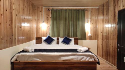ein Schlafzimmer mit einem großen Bett mit blauen Kissen in der Unterkunft Himalayan Cloud's Homestay in Takdāh
