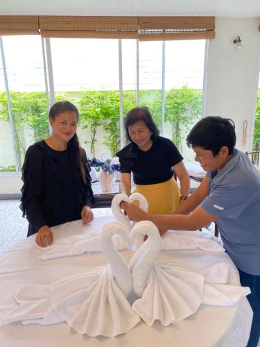 a group of people making swans on a bed at SSIP Boutique Dhevej Bangkok in Bangkok