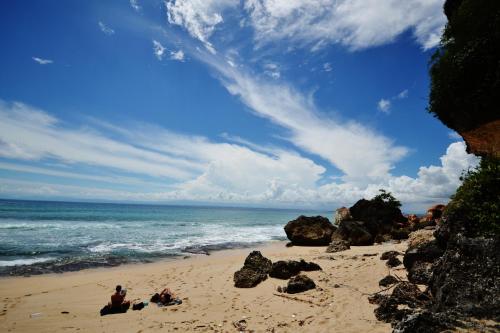 a group of people sitting on a beach near the ocean at Milo's Home in Jimbaran