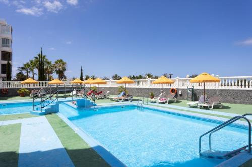 duży basen z parasolami i krzesłami w obiekcie 153 SUNNY Olympia By Sunkeyrents w Playa de las Americas