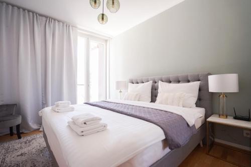 een witte slaapkamer met een groot bed met handdoeken erop bij Exclusive 2-Bedroom condo with Pool & Balcony in Wenen