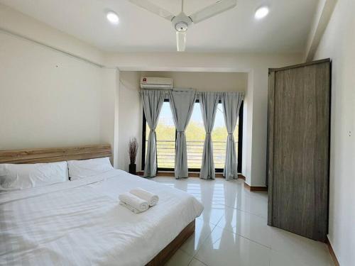 a bedroom with a white bed with two towels on it at BODU ASHI MALDIVES - Central 3 Bedroom Apartment in Hulhumale