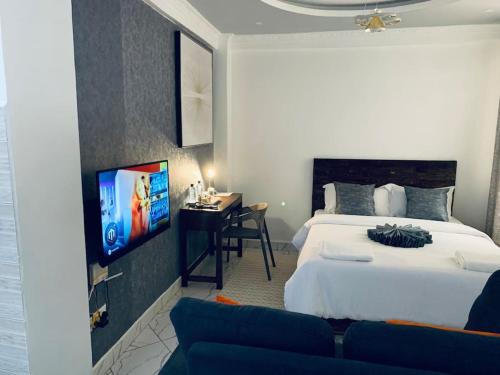 - une chambre avec un lit, un bureau et une télévision dans l'établissement Arabel Studio Apartment, à Nanyuki