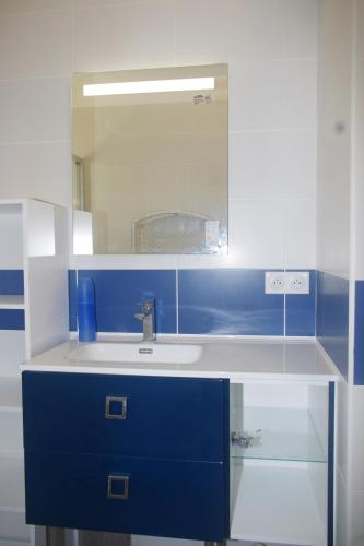 La salle de bains bleue et blanche est pourvue d'un lavabo et d'un miroir. dans l'établissement Villa Nausicaa, à Hyères