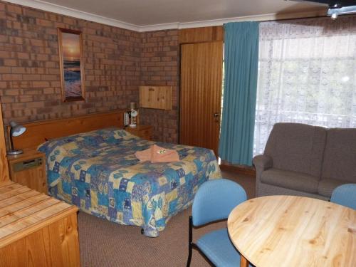 ein Schlafzimmer mit einem Bett, einem Stuhl und einem Tisch in der Unterkunft Wintersun Motel in Victor Harbor